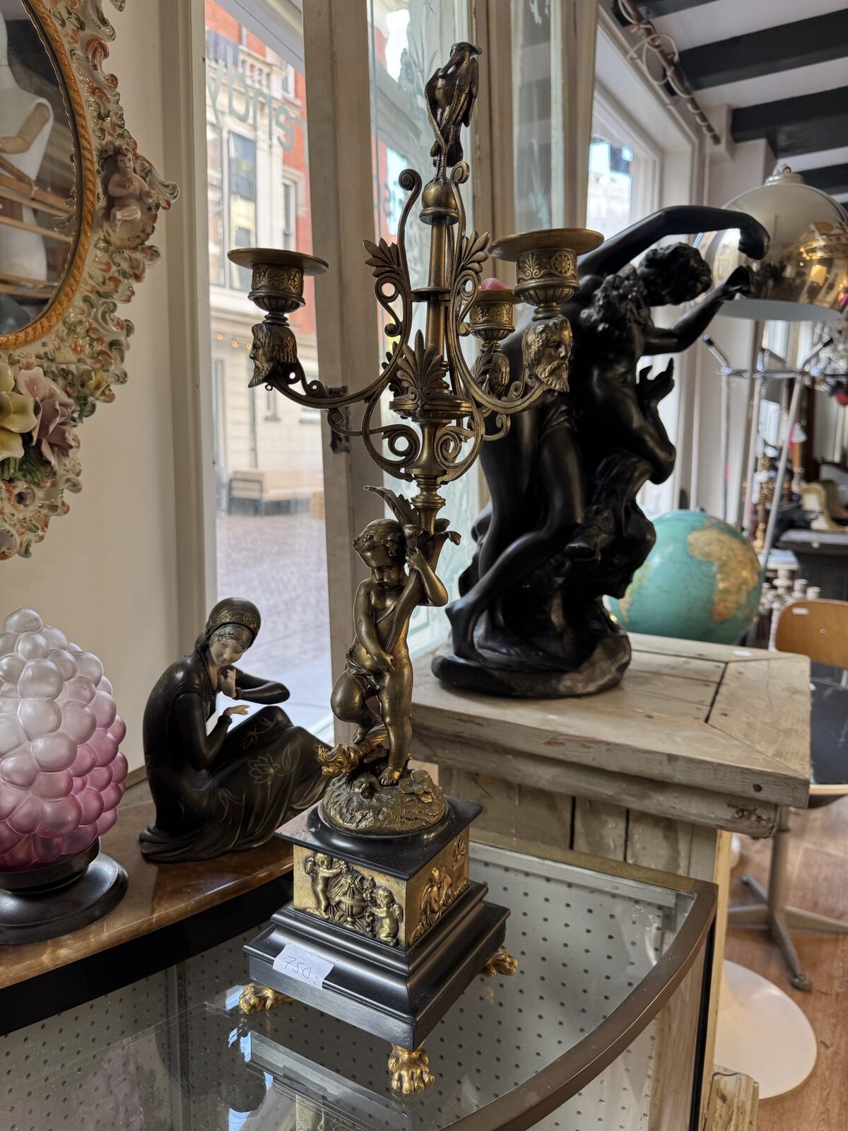 Bronzen kandelaber met figuren op marmeren sokkel in een vitrine